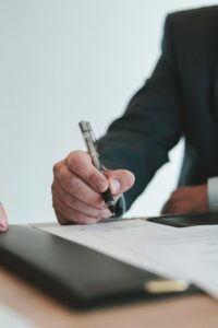 A businessman in a suit signing a contract in an office setting, emphasizing professional context.